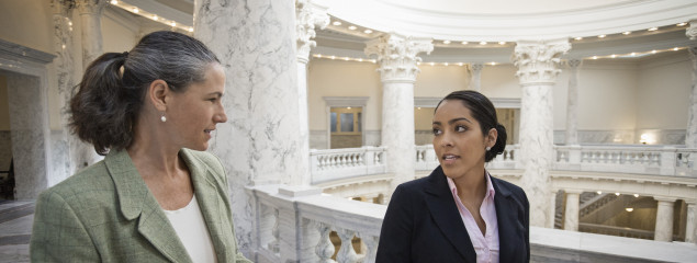 photo of women walking and talking in government building.